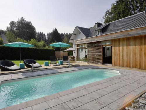斯帕Plushy Holiday Home in Spa with bubble bath Pool的一个带两把椅子和两把遮阳伞的游泳池