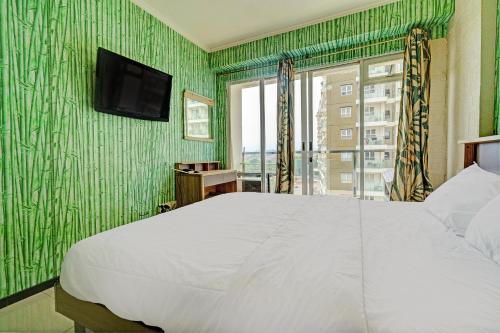 万隆OYO Life 93065 Apartemen Gateway Pasteur By Glory Rent的一间卧室设有一张床,绿色的墙壁上设有一台电视机