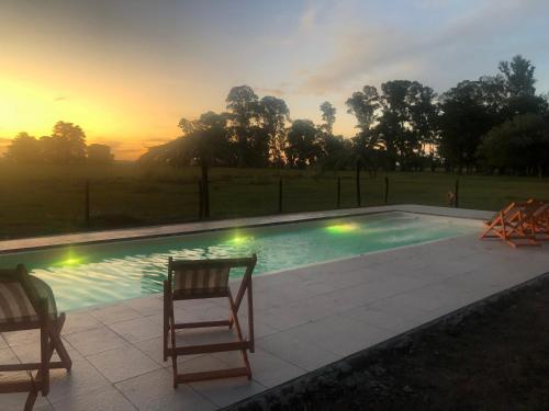 查斯科穆斯Estancia Pedro Chico - Hotel Rural的一个带两把椅子的游泳池,享有日落美景