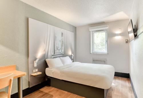 圣让德韦达B&B HOTEL Montpellier 1的酒店客房配有一张床铺和一张桌子。