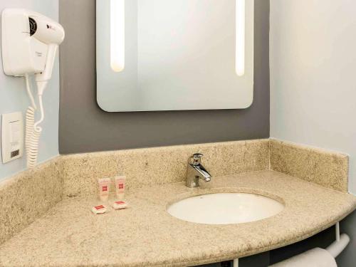马瑙斯ibis Manaus Aeroporto的浴室的柜台设有水槽和镜子