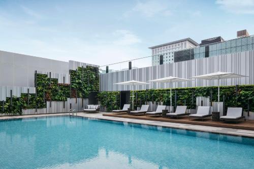 新加坡Hilton Singapore Orchard的一座带椅子和遮阳伞的游泳池位于一座建筑旁边
