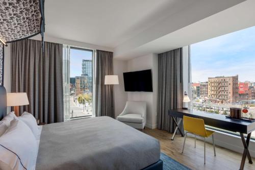 波士顿Canopy By Hilton Boston Downtown的配有一张床、一张书桌和一扇窗户的酒店客房