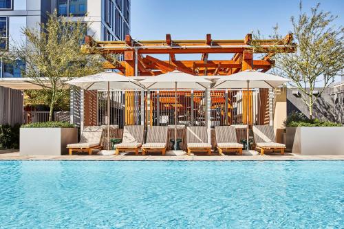 洛杉矶Conrad Los Angeles的一个带躺椅和遮阳伞的游泳池