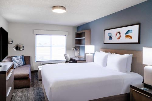 科罗拉多斯普林斯Hyatt House Colorado Springs Airport的一间带白色大床的卧室和一间客厅