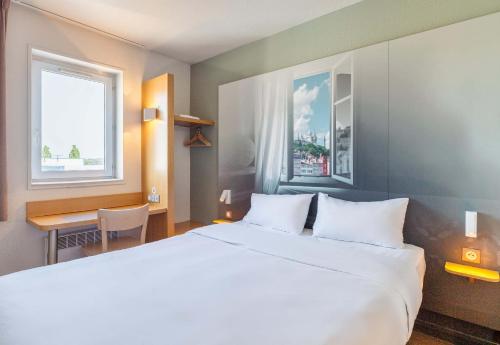 圣博内德米尔B&B HOTEL Lyon Saint-Bonnet Mi-Plaine的卧室配有一张白色大床和一张书桌