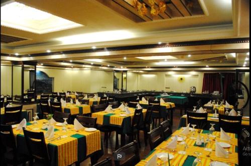 大吉岭Darjeeling La Resort的餐厅设有桌椅,配有黄色和绿色的桌子