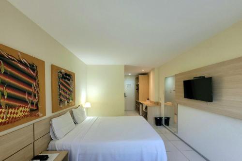 圣路易斯Praiabella Hotel的配有一张床和一台平面电视的酒店客房