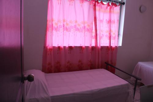 帕皮提HIME LODGE的卧室配有粉红色窗帘和窗户