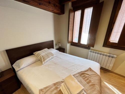 普奇塞达Casa Bernat Apartament的卧室配有一张白色大床和两个窗户
