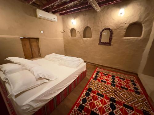 阿尔哈姆拉AL Hamra Heritage Inn的一间卧室配有一张带白色床单和地毯的床。