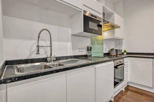 伦敦Heathrow 2-Bedroom Urban Oasis的白色的厨房配有水槽和微波炉