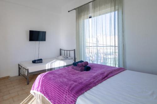 拉里萨Delight apartment LA的一间卧室配有一张床铺,床上铺有紫色毯子
