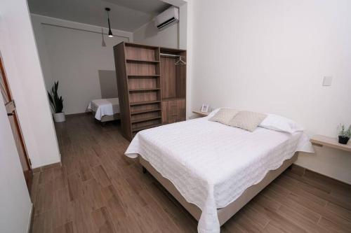塔拉波托CASA MONA 2 - Apartamento en Tarapoto的卧室配有白色的床和书架