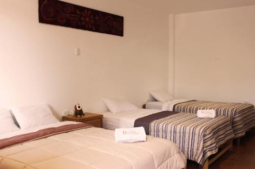 IllimoEcolodge Huaca Piedra的两张位于酒店客房的床,上面有标志