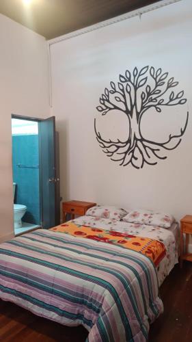 科洛尼亚-德尔萨克拉门托Posada the secret的卧室配有一张床铺,墙上挂着一棵树