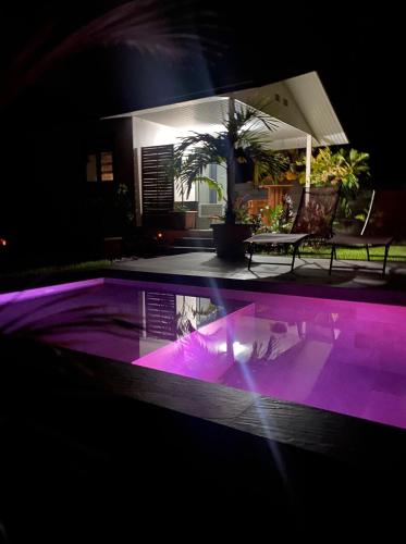 TaravaoTAHITI - Bungalow Toah Toru的游泳池晚上有紫色灯光