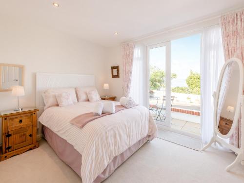 布里克瑟姆Heath Lodge的白色的卧室设有床和大窗户