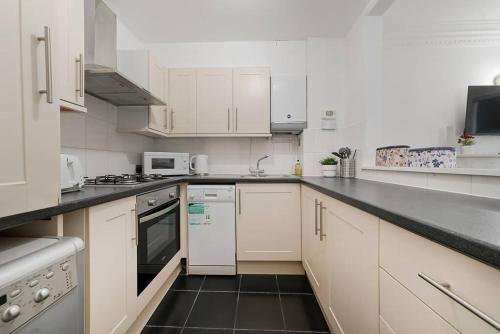 伦敦Knightsbridge Two Bed Apartment的厨房配有白色橱柜和黑色台面