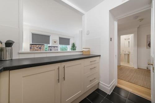 伦敦Knightsbridge Two Bed Apartment的厨房配有白色橱柜和黑色台面