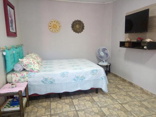 特拉曼达伊Kitnet da Elô的一间卧室配有一张床、一个风扇和一台电视。