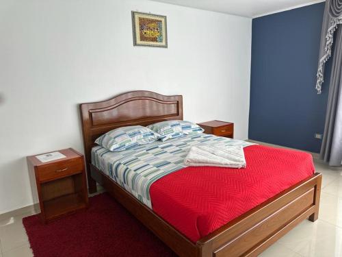伊基克hotel V I D的一间卧室配有一张带红色毯子的床和两张桌子