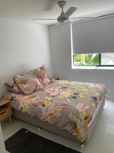 彩虹海滩Rainbow Shores Resort, Baden North的一间卧室配有一张带花卉床罩的床和窗户。