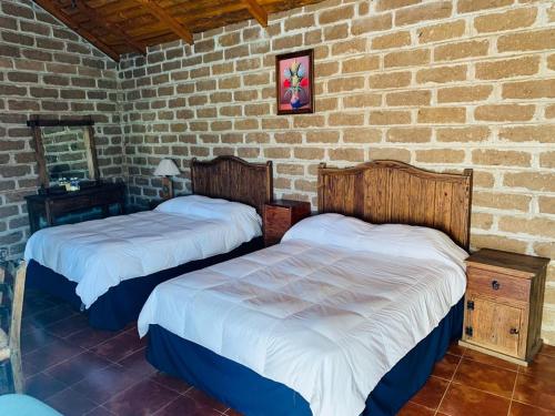 圣米格尔雷格拉Cabañas Los Cactus的砖墙客房的两张床