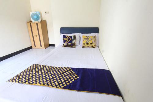 丹戎OYO Life 93157 Kos Kaloka的一间卧室配有一张蓝色和黄色毯子的床
