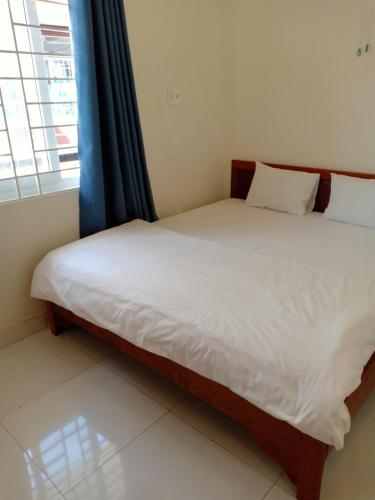 头顿Nhà Nghỉ Linh Quân 1的一间卧室配有一张带白色床单的床和一扇窗户。