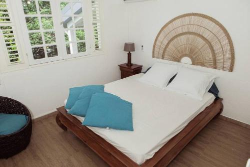 勒拉芒坦Villa F4 chic avec jacuzzi en Martinique的一间卧室配有一张带白色床单和蓝色枕头的大床。