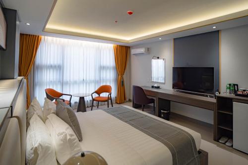 KababaeSubic Riviera Hotel & Residences的酒店客房配有一张床、一张书桌和一台电视。