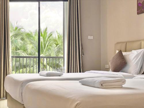 南邦椰子酒店 的配有大窗户的酒店客房内的两张床