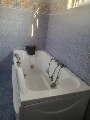 基加利ASMERA GUEST HOUSE的浴室铺有蓝色瓷砖,配有白色浴缸。