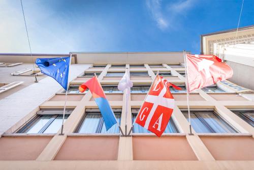 卢加诺San Carlo Apartments的建筑物一侧的三面旗