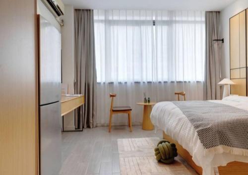 上海自在居酒店式公寓（虹桥龙柏新村店）的一间卧室配有一张床、一张书桌和一个窗户。
