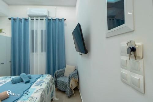 雅典'The Aqua'House Project In Athens的一间卧室配有一张床、一台电视和一把椅子