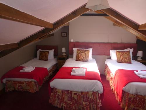 斯基普顿The George Inn的一间设有两张红色和白色床单的房间