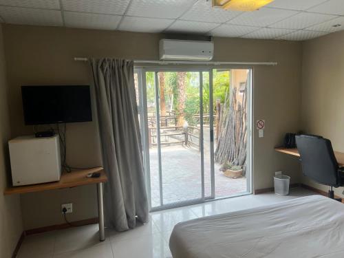 温当瓦Ondangwa Rest Camp的一间卧室设有一张床和一个滑动玻璃门