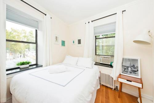 纽约Three Bedroom West Village Townhouse的白色卧室设有一张大床和两个窗户