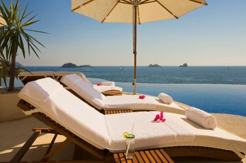 伊斯塔帕伊斯塔帕大海小溪度假酒店及Spa的海滩上一组带遮阳伞的床