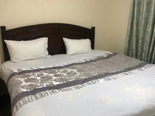 内罗毕the botanical bliss 1 bedroom的一张带木制床头板的床和两个枕头