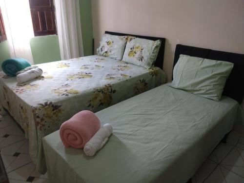 穆库热Aluga-se uma casa em Mucugê Bahia的一间卧室配有两张床,一张桌子上挂着粉红色的帽子