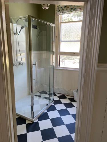 BeaconsfieldThe Exchange Hotel - Offering Heritage Style Accommodation的浴室设有玻璃淋浴间和 ⁇ 格地板