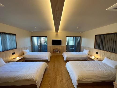 桑名市machiyado Kuwanajuku Edomachi 21的一间酒店客房,设有三张床和一台平面电视