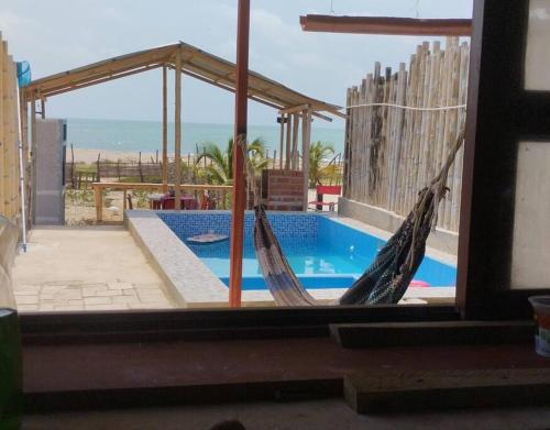 通贝斯Acogedora casa frente al mar的一个带吊床的门廊和一个游泳池