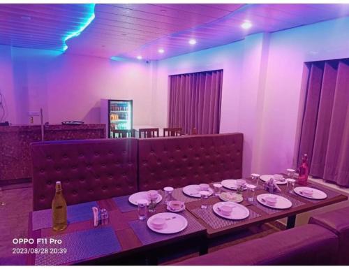 西姆拉Hotel Candle Wood, Shimla的一张带盘子的长桌和一瓶葡萄酒