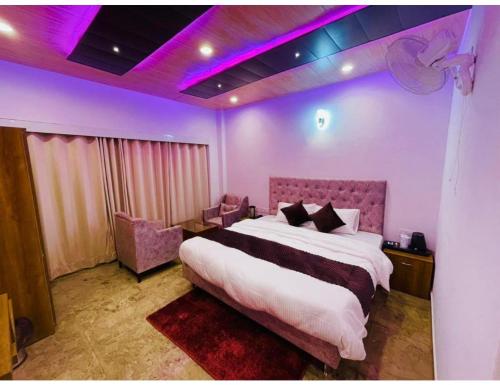 西姆拉Hotel Candle Wood, Shimla的一间卧室配有一张大床和紫色照明