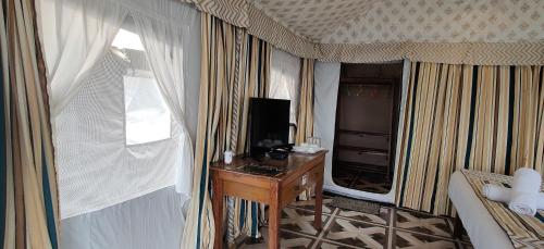 达兰萨拉Beaumont Glamping Eco Resort的客房设有书桌、床和窗户。