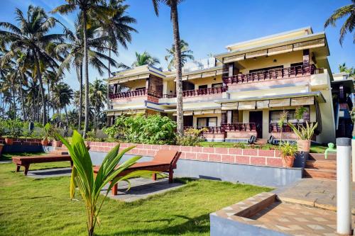 瓦尔卡拉Maadathil Beach Resort的一座棕榈树大房子前面